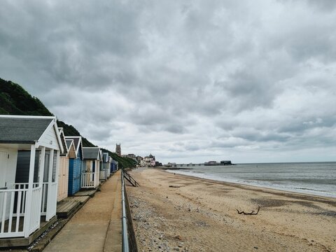 Cromer Beach in England on a gloomy day with wooden houses on the shore and gray clouds in the sky