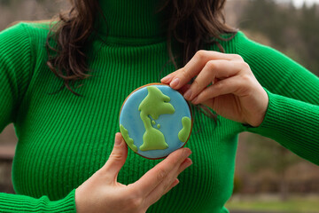 Earth Day concept. Gingerbread in the shape of a planet in the hands of a woman. - 782919449