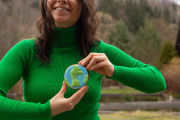 Earth Day concept. Gingerbread in the shape of a planet in the hands of a woman. - 782919453