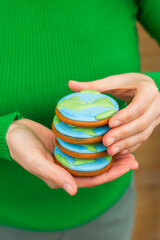 Earth Day concept. Stack of cookies in the shape of the Earth in female hands. - 782919476