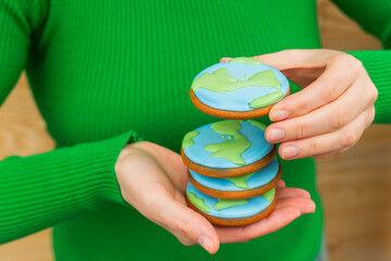 Earth Day concept. Stack of cookies in the shape of the Earth in female hands.