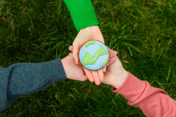 Earth Day concept. Hands hold gingerbread in the shape of the Earth. Care for the environment. - 782919603