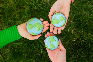 Earth Day concept. Hands hold gingerbread in the shape of the Earth. Care for the environment. - 782919643