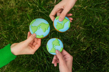 Earth Day concept. Hands hold gingerbread in the shape of the Earth. Care for the environment. - 782919648