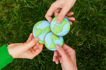 Earth Day concept. Hands hold gingerbread in the shape of the Earth. Care for the environment. - 782919672
