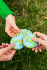 Earth Day concept. Hands hold gingerbread in the shape of the Earth. Care for the environment. - 782919690