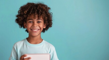 photo of Curly latino boy o pastel blue background holding tablet smiling with toothy smile...