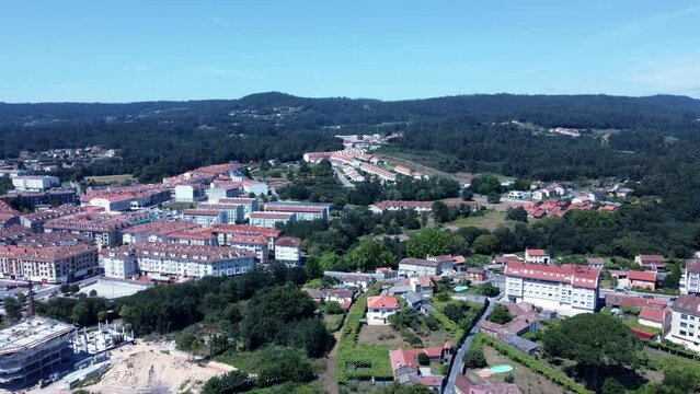 Bird's eye view of houses on green hills on a sunny day in Ames, Spain