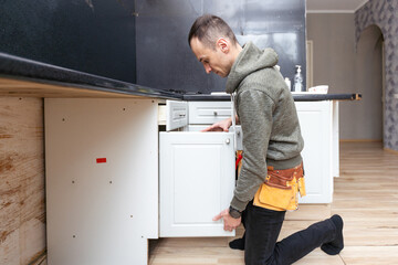 Older man disassembling apartment kitchen out of service - obrazy, fototapety, plakaty