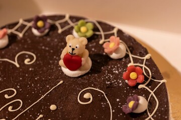 Closeup of a chocolate cake decorated with flowers on a tray with a blurry background