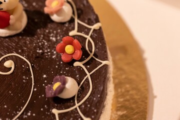 Closeup of a chocolate cake decorated with flowers on a tray with a blurry background