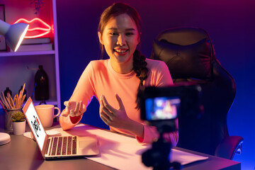 Smiling creative young beautiful Asian influencer recording on camera with positive podcast speech...