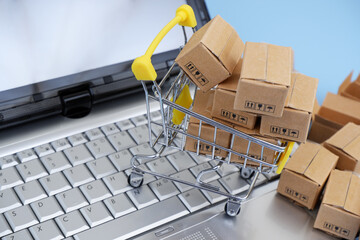 Shopping cart, and many carton boxes on computer keyboard. Online shopping and selling concept.