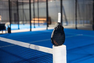 Paddle tennis: Paddel racket and ball in front of an outdoor court