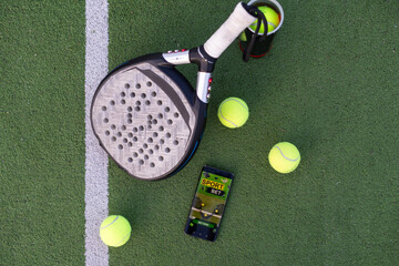 A tennis ball, a racket and a mobile phone with a put screen lie on a blue background. The concept of advertising a tennis club or ordering services. Horizontal photo