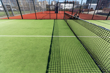 Obraz premium Landscaped areas of a residential development with a tennis court with high Plexiglas and metal fences