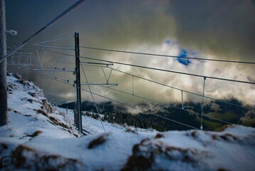 Scenic shot of the lines of a ropeway in snowy mounts under the cloudy sky