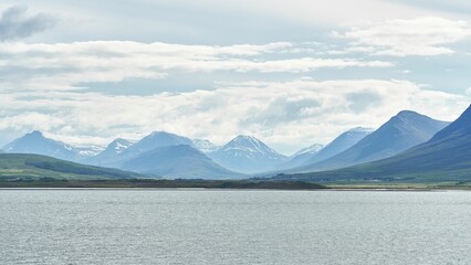 Snowcap mountain range from the lake on cloudy sky background in Iceland