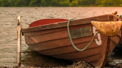 Closeup shot of a small rowboat on the shore of the lake during sunset