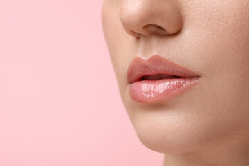 Woman wearing beautiful lip gloss on pink background, closeup. Space for text