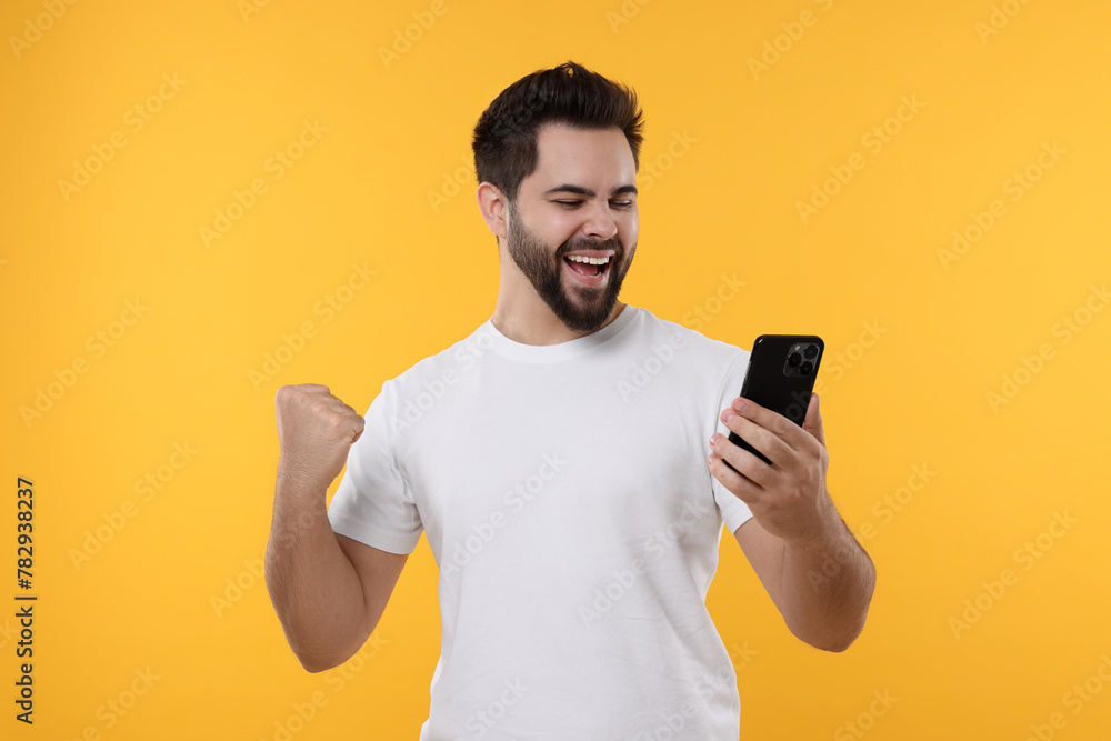 Sticker Happy young man using smartphone on yellow background