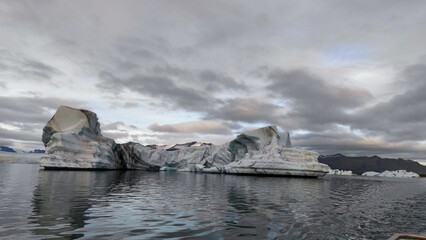 Floating icebergs in the water against a cloudy sky