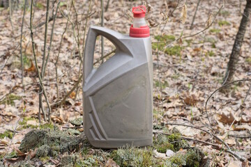 one old dirty gray plastic canister stands on green moss and stump outdoors in nature