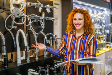 Portrait of buyer in bathroom store. Redhead woman is choosing faucet for her apartment.