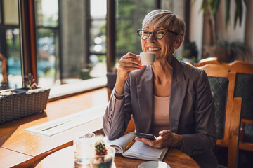 Mature woman is sitting in cafe and relaxing.