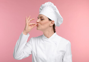 Happy woman chef in uniform showing perfect sign on pink background