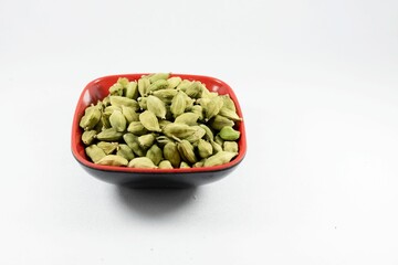 Pile of green cardamom in a bowl isolated on white background