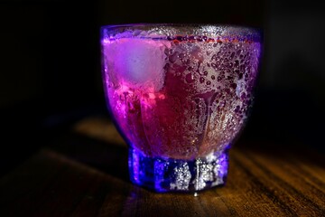Closeup of a glass of a cold cocktail on a wooden table. Nightclub drink.