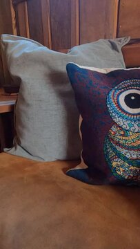 Vertical view of colorful pillows with owl and cats images on a couch