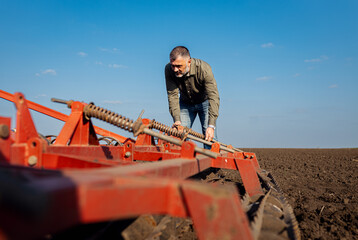 Portrait of mature farmer standing in field preparing to cultivate the land with a tractor.