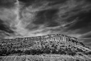 Desert mountain against a cloudy sky, grayscale shot