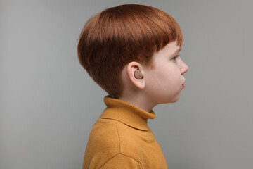 Little boy with hearing aid on grey background