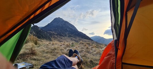 Beautiful shot of a hiker's feet from a camping tent to the Glyder Fach mountain peak