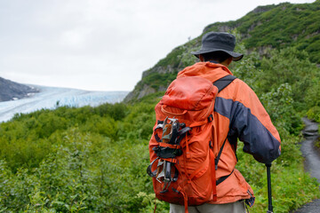 Man carrying ice crampons on his backpack, hiking towards Exit Glacier.  Kenai Fjords National Park. Alaska.