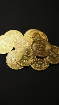 A pile of bitcoins golden coins on a black background, camera rotation view, vertical shot. Bullish BTC, cryptocurrency, 2p2 exchange and blockchain concept