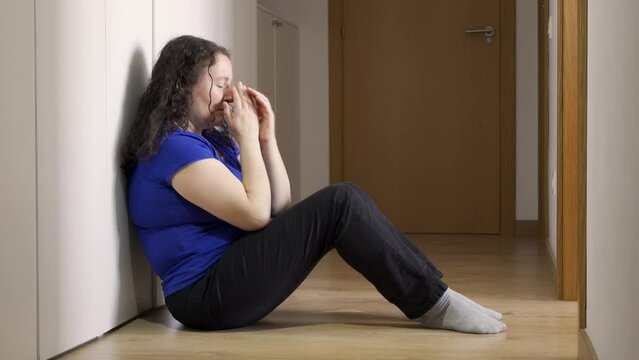 Upset problem woman with head in hands sitting on floor concept for bullying, depression stress or frustration at home