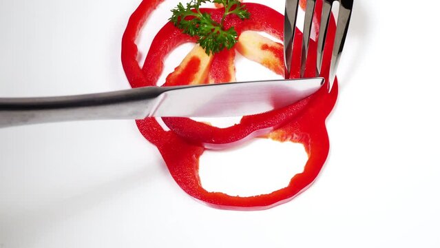Cutting red Pepper - Vegetables with fork and knife on a white background 