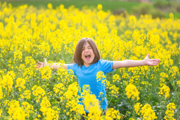 Naklejka na ściany i meble Five-year-old boy screaming with open arms in a rapeseed meadow.