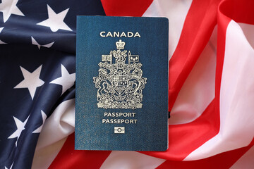 Canadian passport on United States national flag background close up. Tourism and diplomacy concept