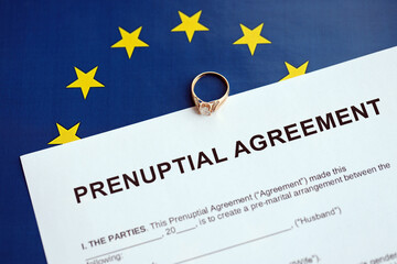 Prenuptial agreement and wedding ring on table. Premarital paperwork process in europe close up