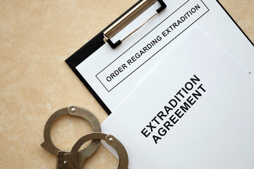 Extradition Agreement and Order Regarding Extradition with handcuffs on table close up