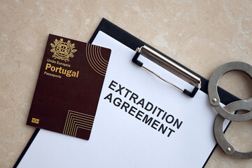 Passport of Portugal and Extradition Agreement with handcuffs on table close up