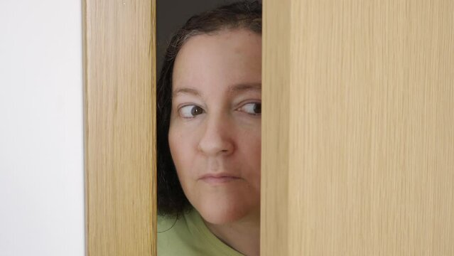 Woman spying and entering through the door as concept of nosy woman