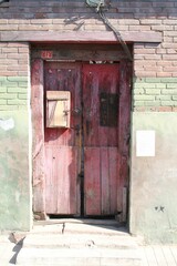 Vertical closeup shot of an old red wooden door of a building on a sunny day