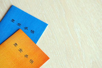 Japanese pension insurance booklets on table. Blue and orange pension book for japan pensioners close up