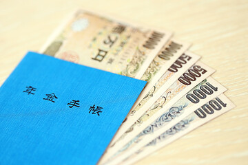 Japanese pension insurance book on table with yen money bills. Blue book for japan pensioners close up